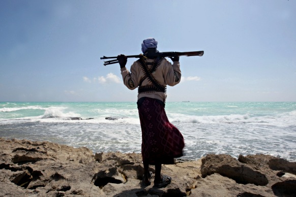 (FILES) -- A file photo taken on January 7, 2010 shows an armed Somali pirate along the coastline while the Greek cargo ship, MV Filitsa, is seen anchored just off the shores of Hobyo, northeastern Somalia, where its being held by pirates. On the 20th anniversary of president Mohamed Siad Barre's ouster that triggered Somalia's descent into chaos and one of Africa's longest civil wars, prospects for peace remain slim, analysts said. The Horn of Africa country is now best known to the outside world for being the place that inspired the Hollywood war movie 